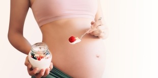 A pregnant person eating yogurt