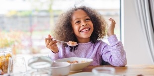 A girl smiles as she eats a healthy, nutritious meal