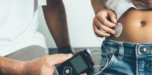 A young child with diabetes uses an automated insulin delivery system