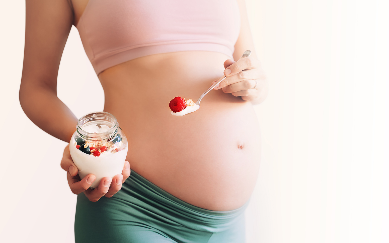 A pregnant person eating yogurt