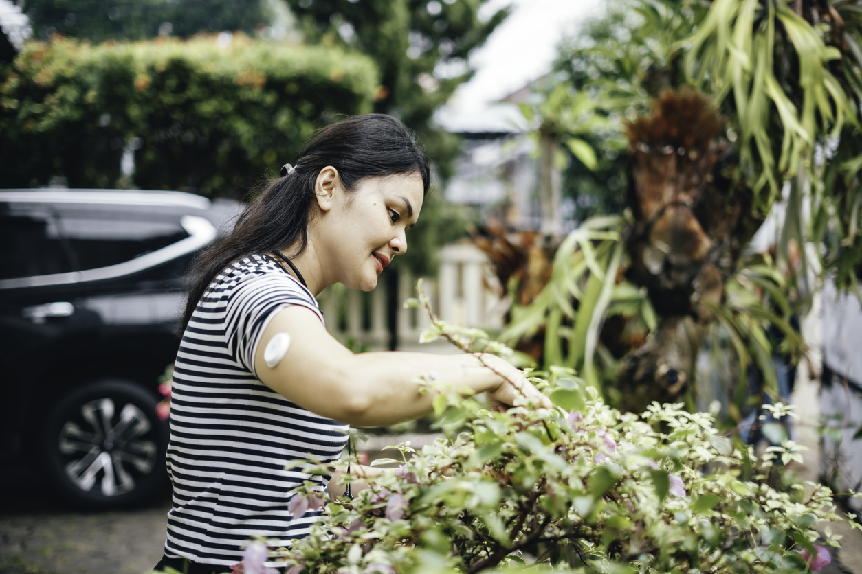 A woman examines flowers while wearing a CGM