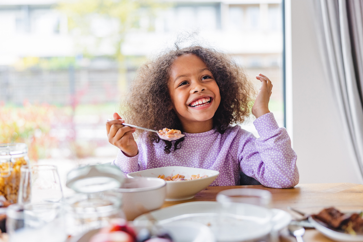 A girl smiles as she eats a healthy, nutritious meal