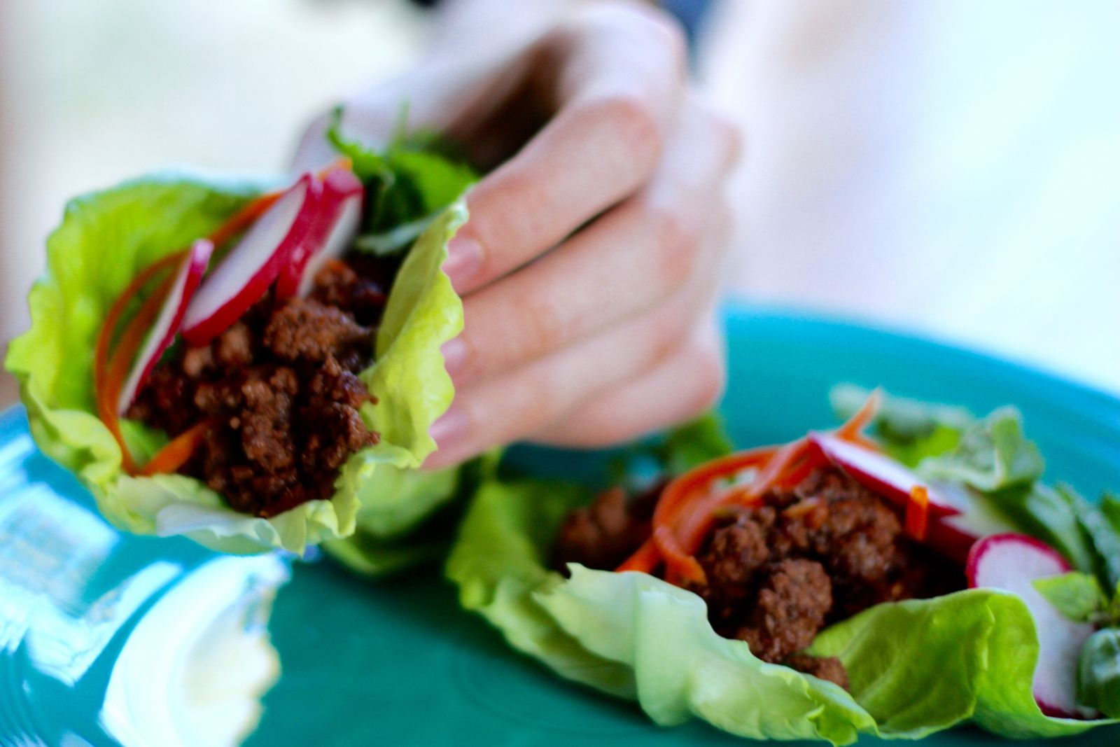 Woman's hand picking up Asian-Style Lettuce Wraps