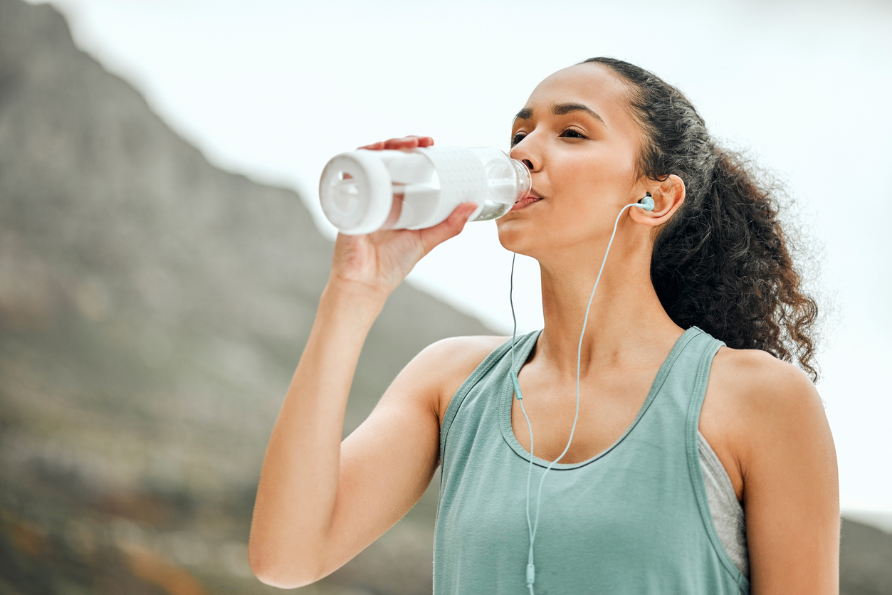A woman stays hydrated during a workout by drinking from a water bottle