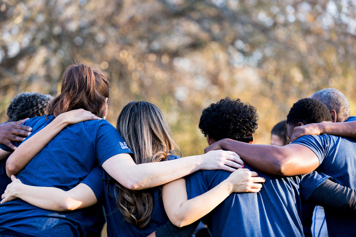 Group of people with arms around each other in a huddle 