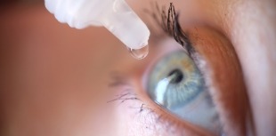 A person receives eye drop treatment