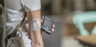 A person uses AID technology to manage their diabetes