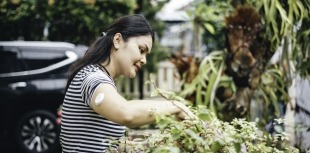 A woman examines flowers while wearing a CGM