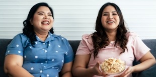 Women with obesity enjoy some popcorn while watching a movie