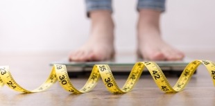 Person weighing themselves on scale