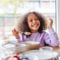 A girl smiles as she eats a healthy, nutritious meal