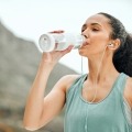 A woman stays hydrated during physical activity by drinking from a water bottle